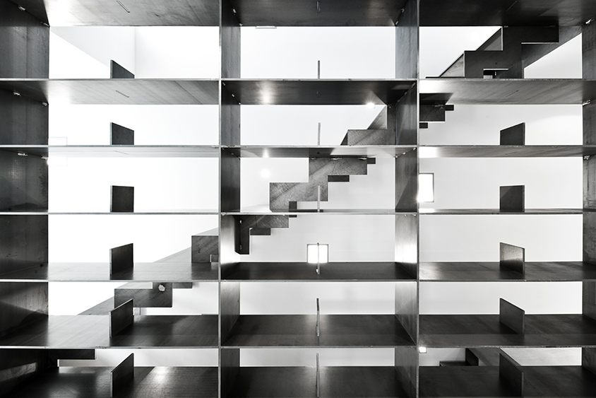 Als begehbare Raumskulptur konzipiert, verbindet die kombinierte Treppen-Regal-Konstruktion drei Ebenen des Gebäudes.