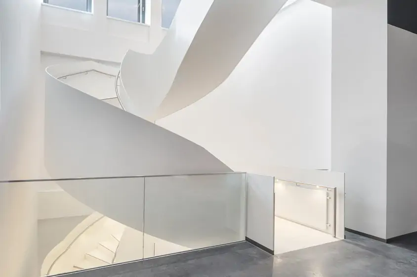 Geschäftstreppe in der Sparkasse: gebogene Wangentreppe aus Stahl, weiß lackiert