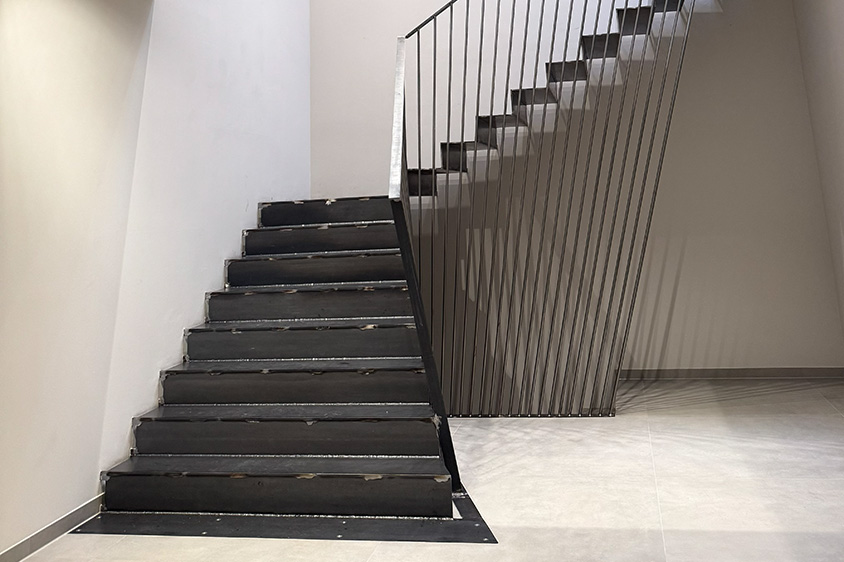 Faltwerktreppe aus Stahl mit schrägem Geländer als Treppe in einem Firmengebäude