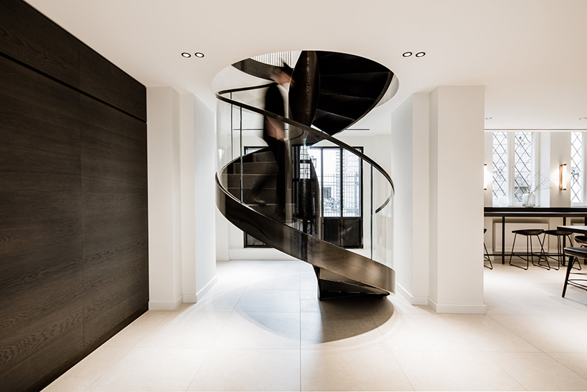 skulpturale Spindeltreppe aus Stahl mit durchlaufendem Glasgeländer im Bürogebäude