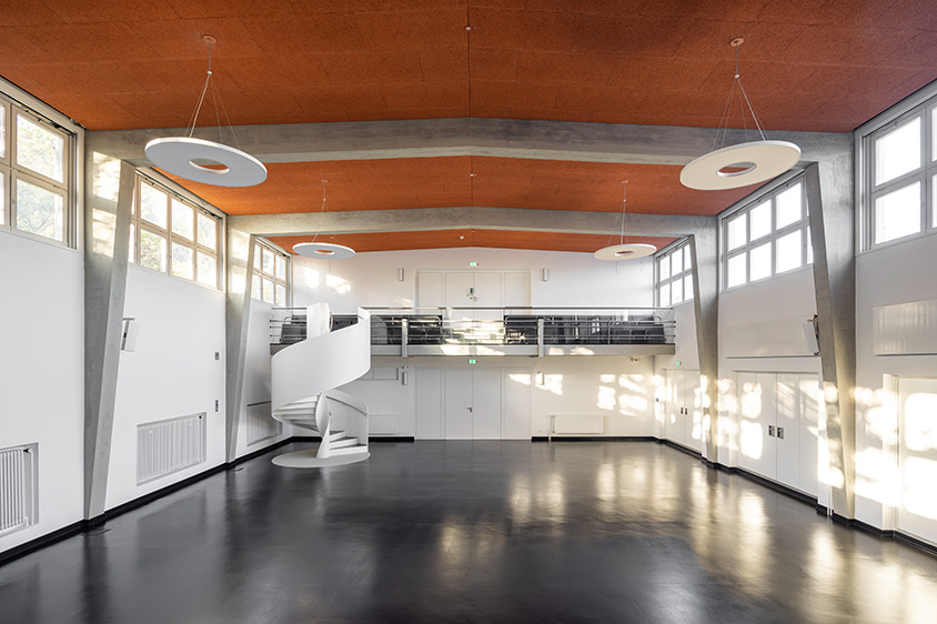 Spindeltreppe aus Stahl in weiß als Schulhaustreppe in einer Aula einer Schule - Bauen im Bestand